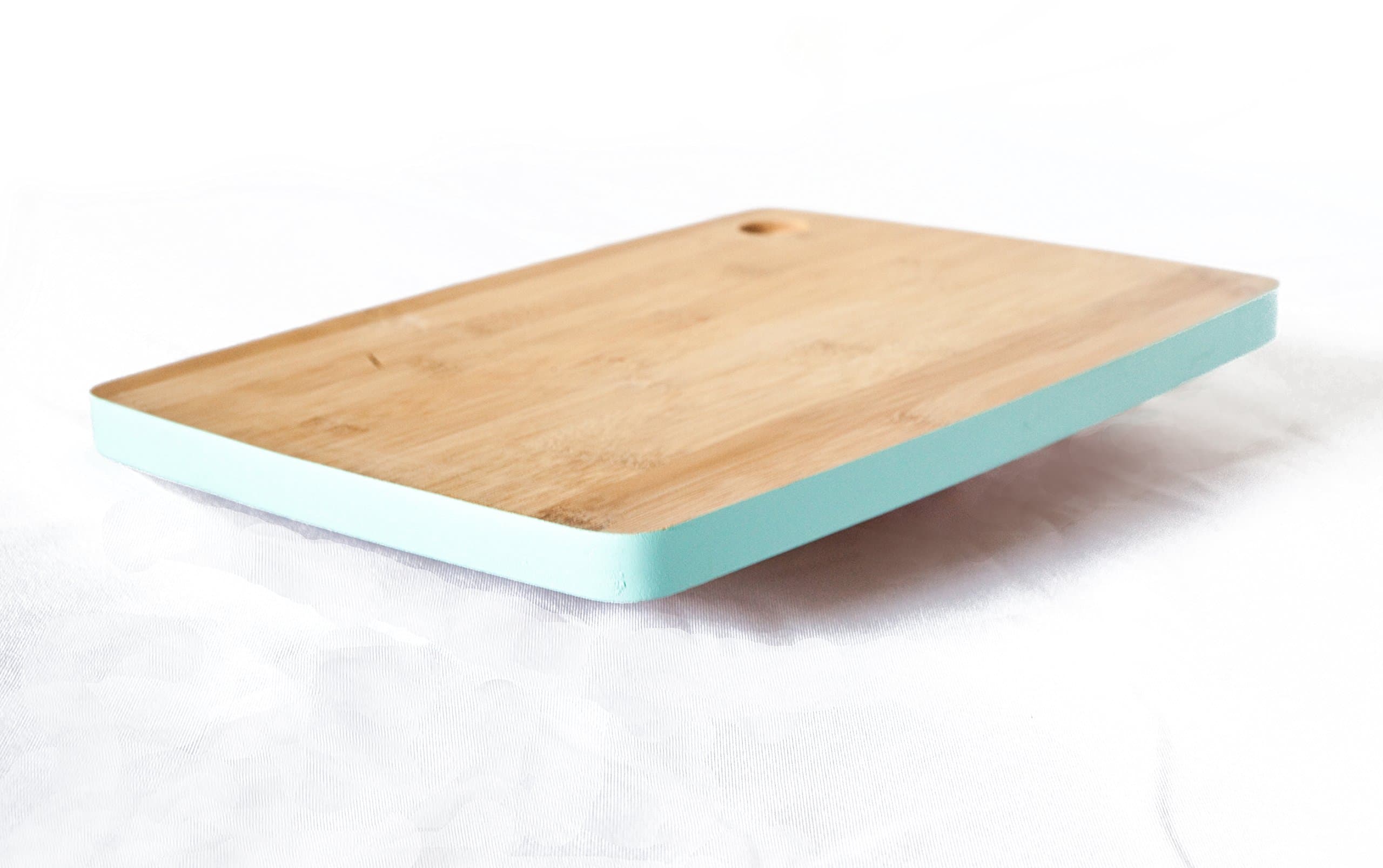 Natural Bamboo Wood Cutting Board with Teal Border. Brings simple elegance to your kitchen. Small-medium size. Cut Out Handle for easy space saving storage.